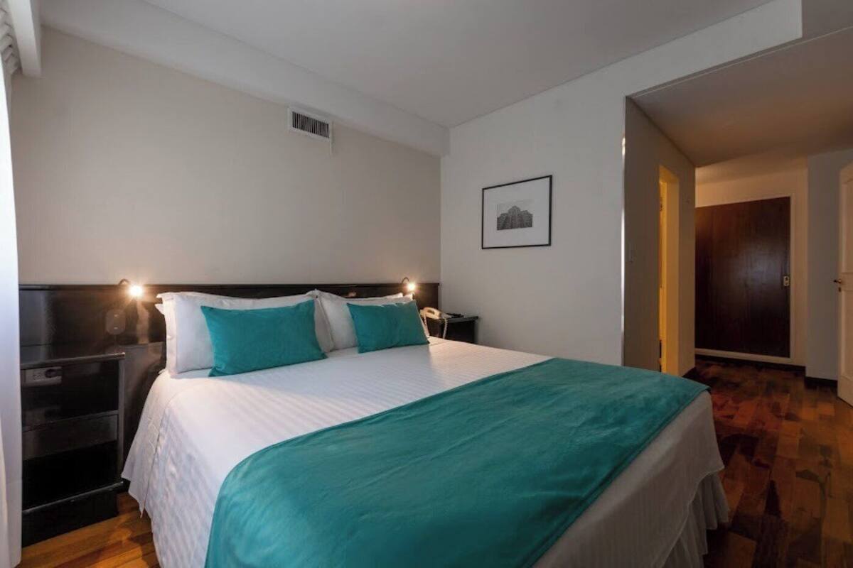 A neatly arranged bedroom with a bed, bedside tables, and a framed picture on the wall.