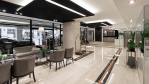 A modern lobby with a seating area, a reception desk, and a car parked outside. - Feir's Park Hotel (Buenos Aires)
