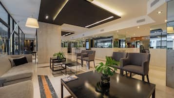 Un vestíbulo moderno con un sofá, sillones, una mesa de centro y un mostrador de recepción.