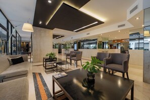 A modern lobby with a sofa, armchairs, a coffee table, and a reception desk. - Feir's Park Hotel (Buenos Aires)