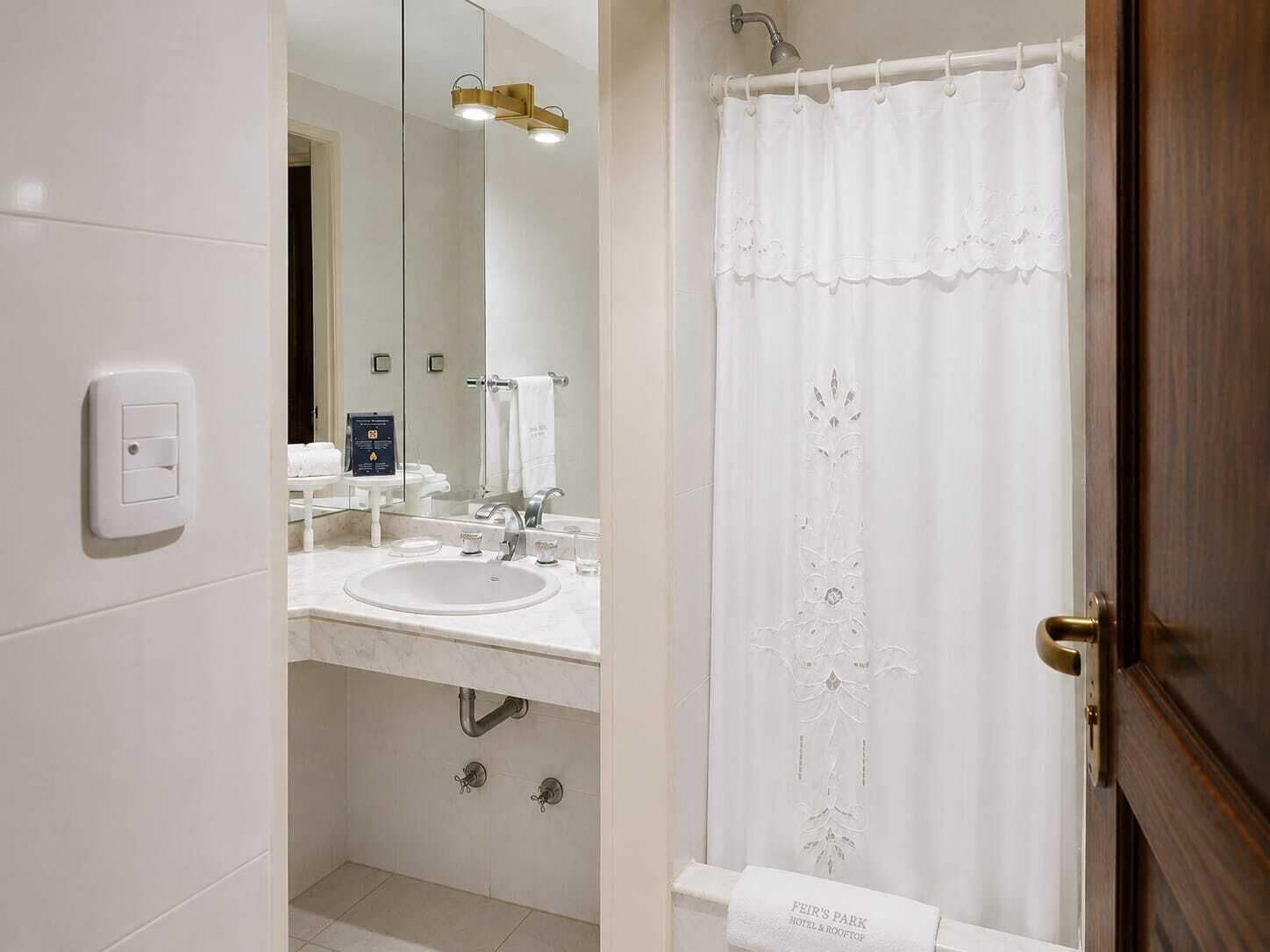 Un baño moderno con lavamanos, espejo y cortina de ducha.