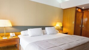 Ein Hotelzimmer mit einem Bett, zwei Nachttischen, einer Lampe, einem Telefon und einem Kleiderschrank.