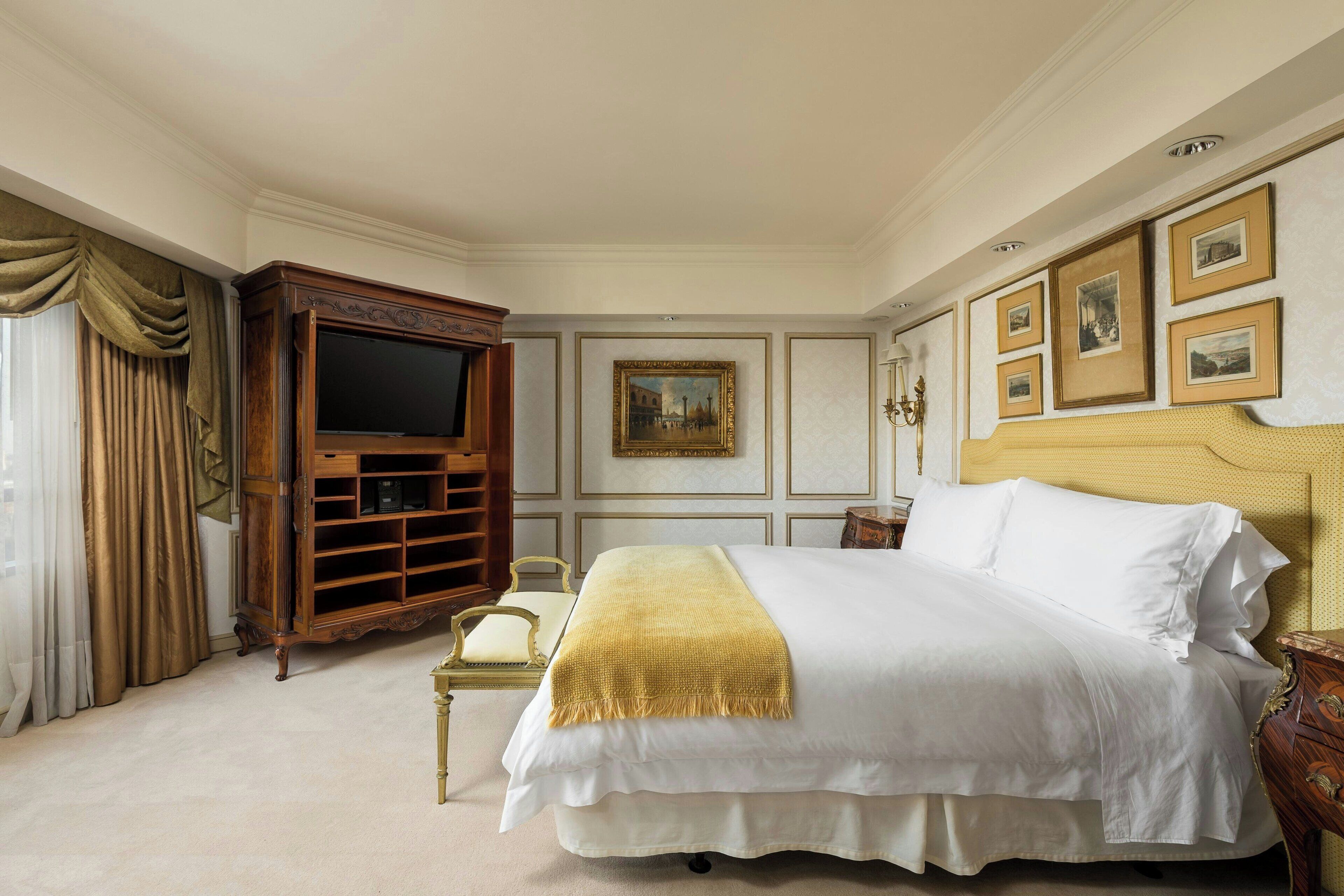 Ein großes Bett mit Kopfteil, ein Holz-Fernsehschrank und ein Bild an der Wand.