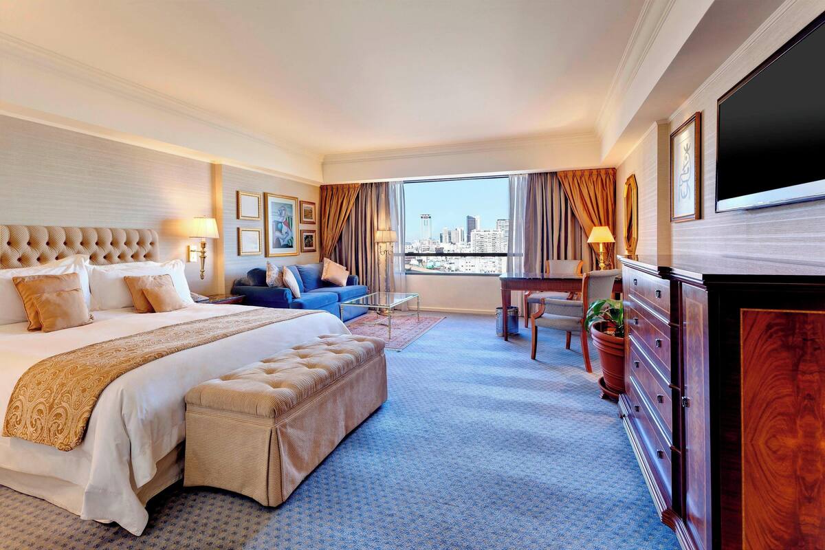 A hotel room with a large bed, a sofa, a desk, and a TV.