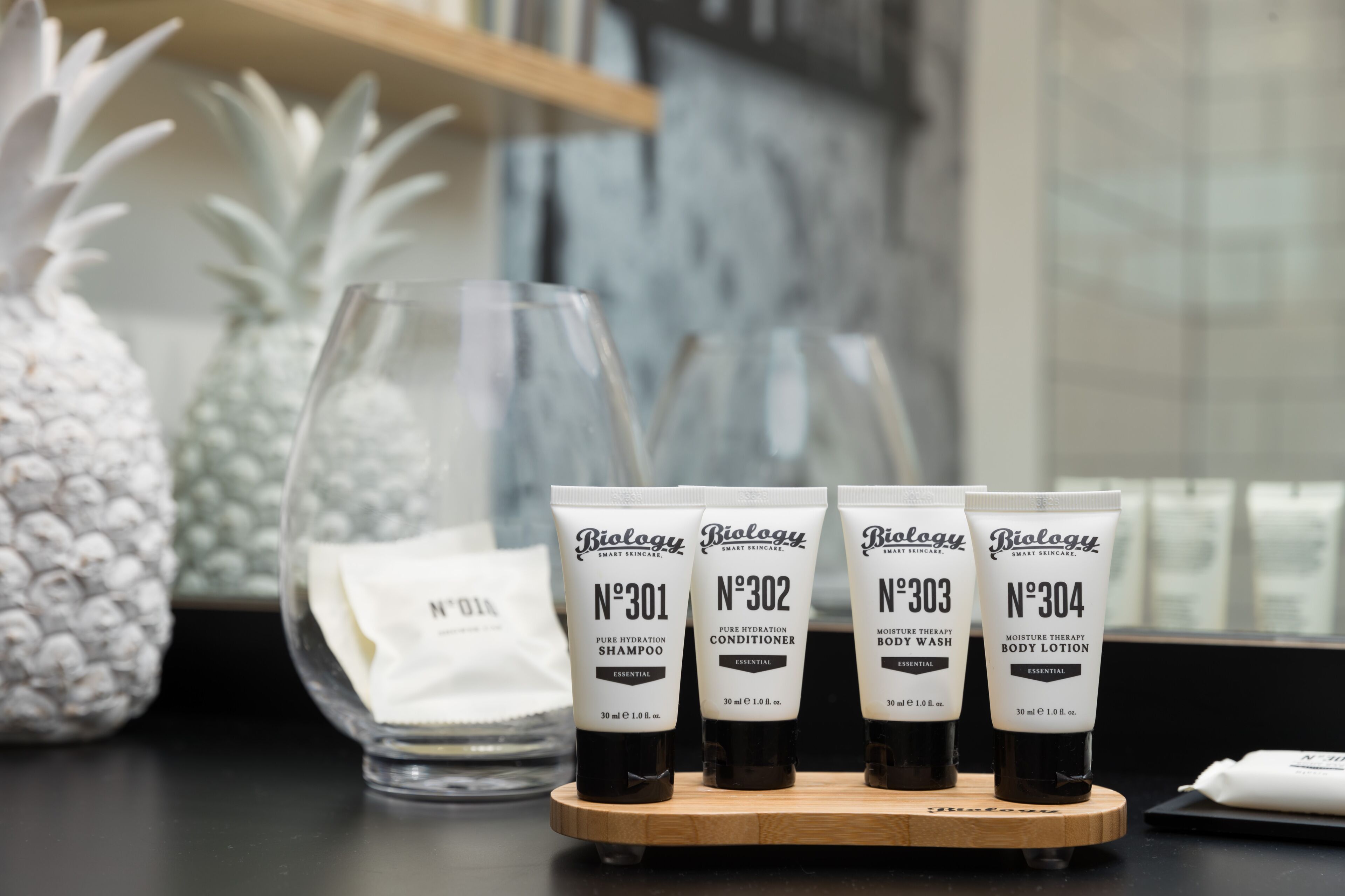 Four bottles of Biolgy skincare products on a wooden tray.