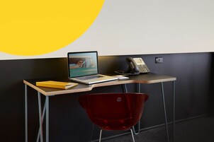Un escritorio moderno con una computadora portátil, un teléfono y una carpeta amarilla.