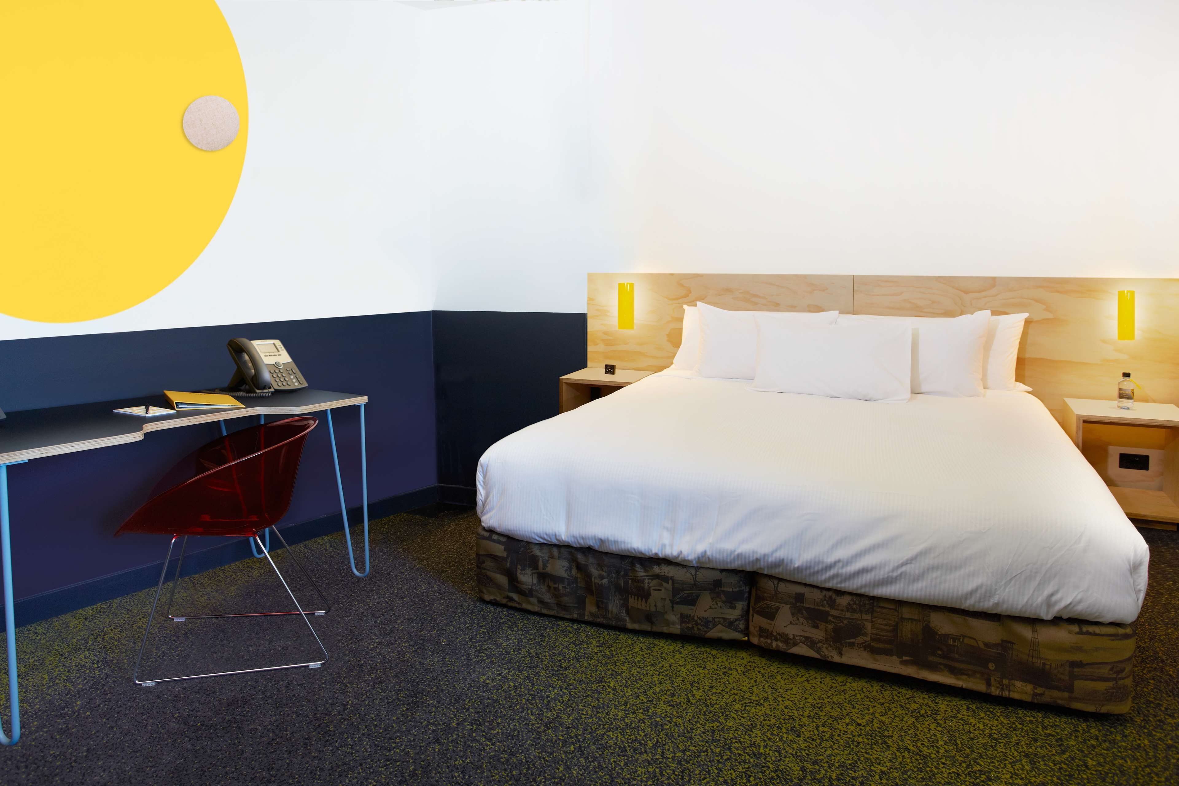 A hotel room with a bed, bedside tables, a desk, and a chair.