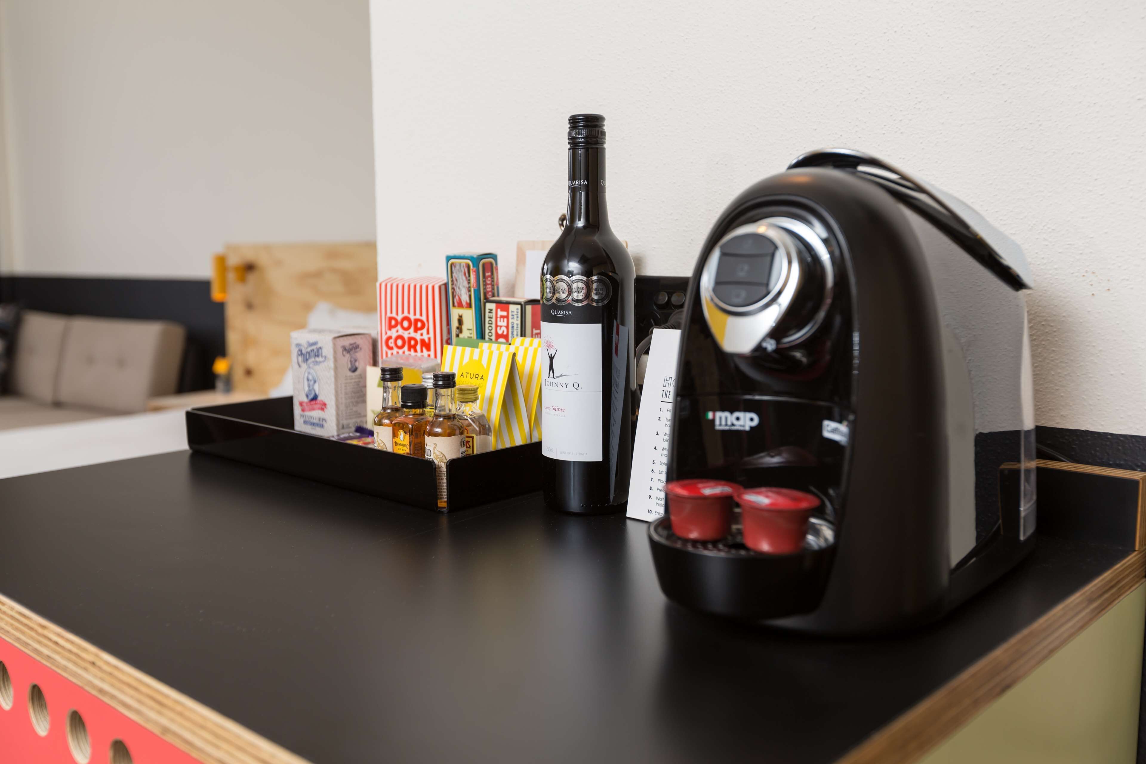 Una encimera de cocina con cafetera, botella de vino y diferentes condimentos y aperitivos.