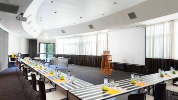 A conference room with a long table, chairs, and a projector screen.