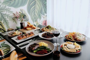 A dining table with various dishes and drinks, set against a backdrop of a large botanical print. - Mercure Albury (Albury)