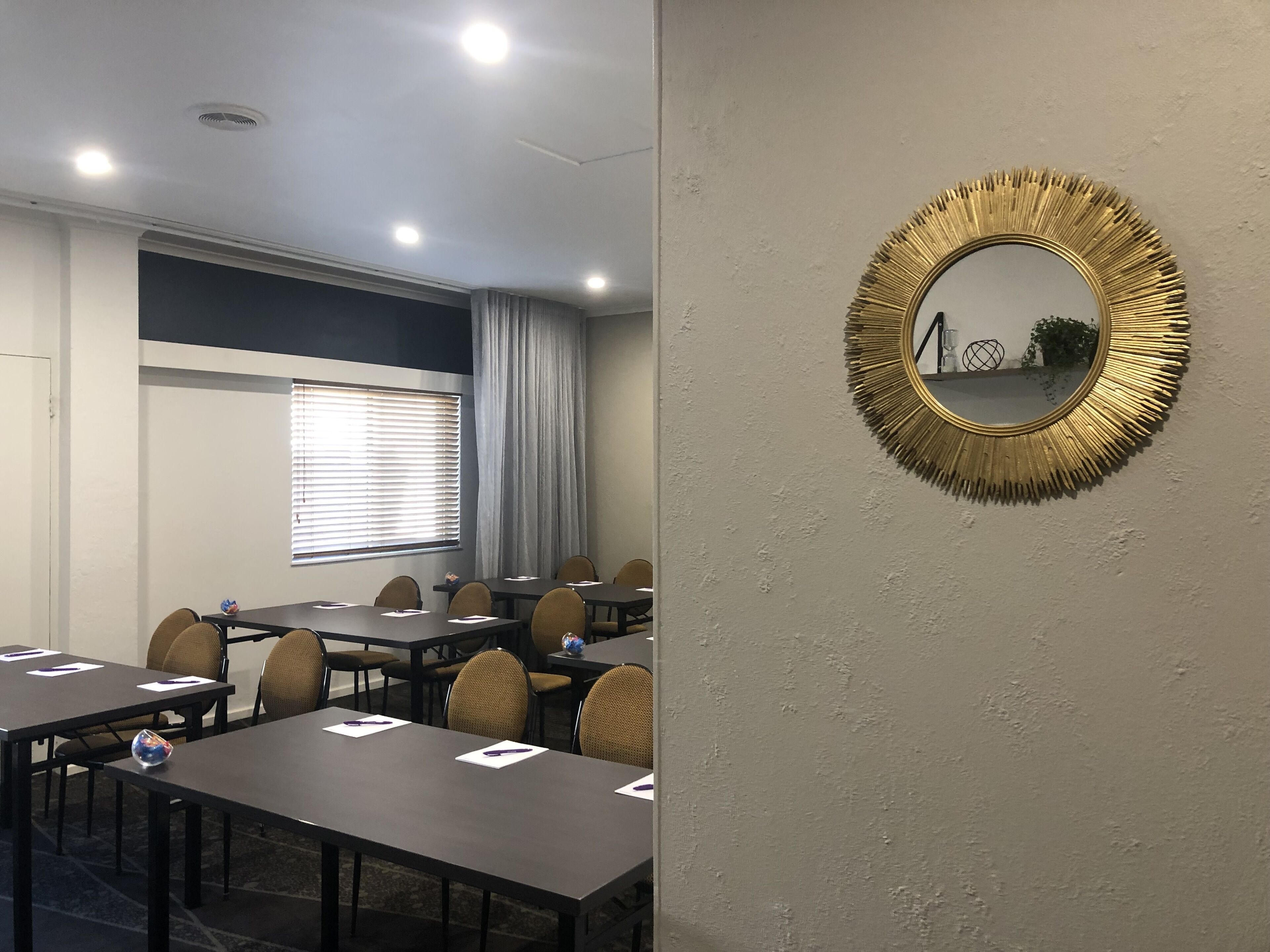 A conference room with tables, chairs, and a large mirror on the wall.