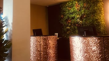 A reception area with a green wall and two metallic reception desks.