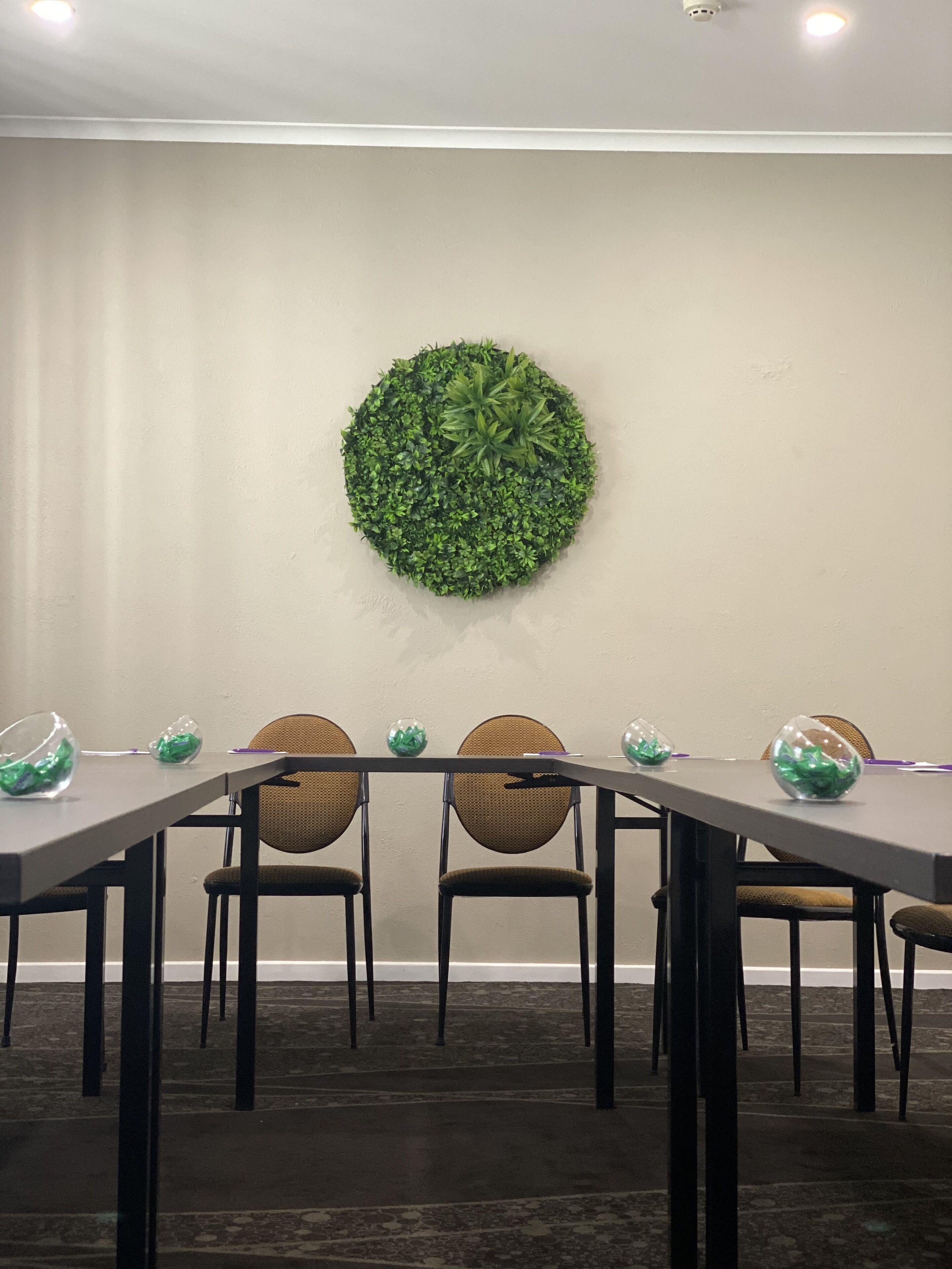 Une salle de conférence équipée d’une table ronde, de quatre chaises et d’une décoration murale verte.