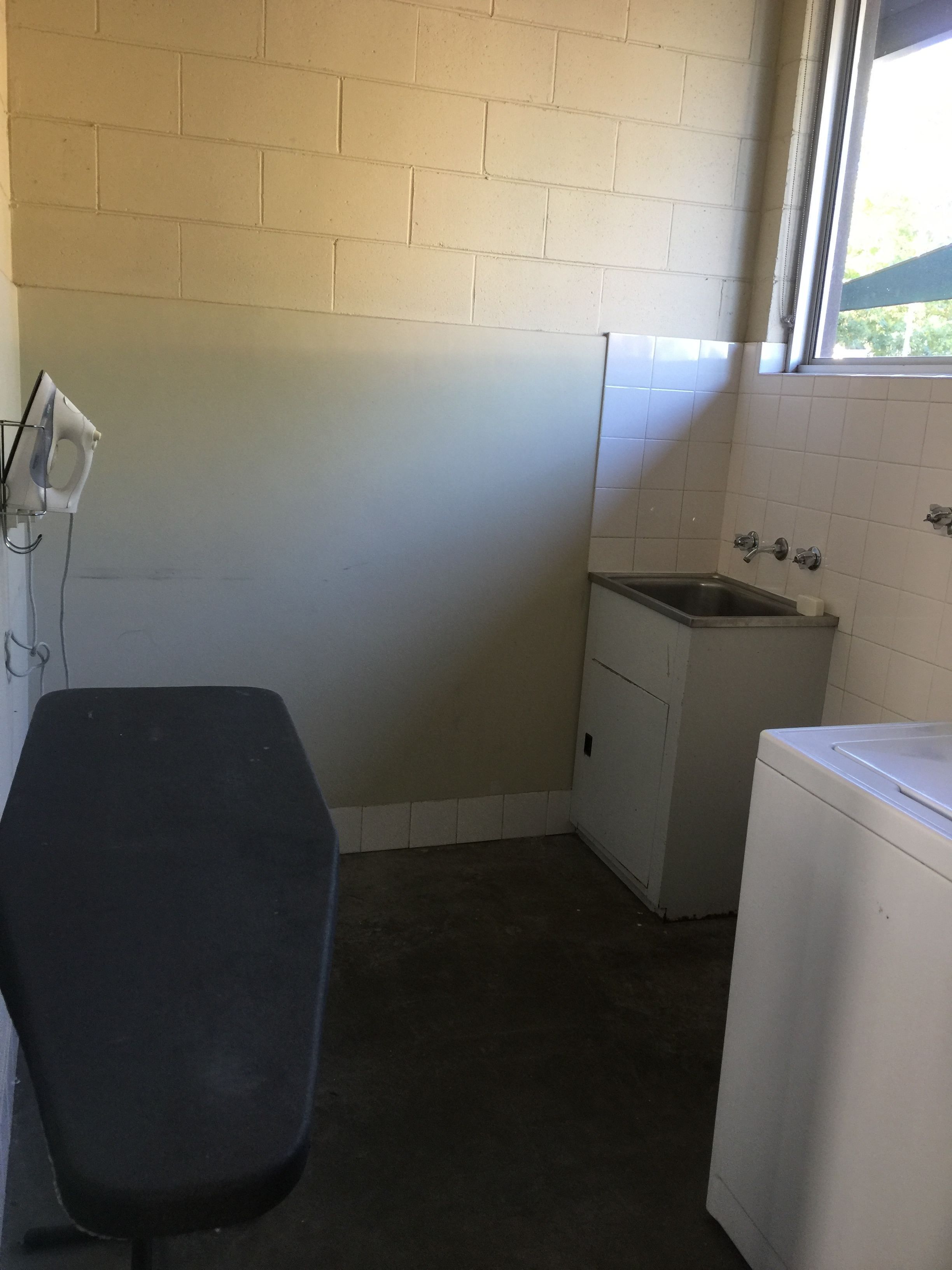 A small laundry room with a washing machine, a sink, and a chair.