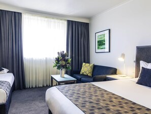 A hotel room with a bed, two bedside tables, a sofa, a desk, and a window with curtains. - Mercure Albury (Albury)