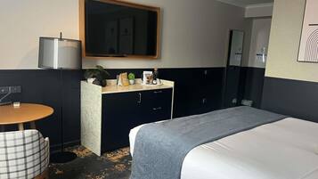 Une chambre d’hôtel avec un lit, un bureau, une chaise, un miroir et une petite table.
