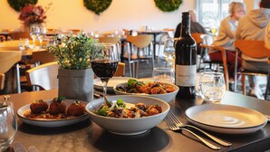 Une table à manger avec des assiettes remplies de nourriture, une bouteille de vin et des verres.