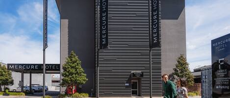 The exterior of the Mercure Hotel with a modern facade, a visible entrance, and a sign for the Fabric Restaurant & Bar.