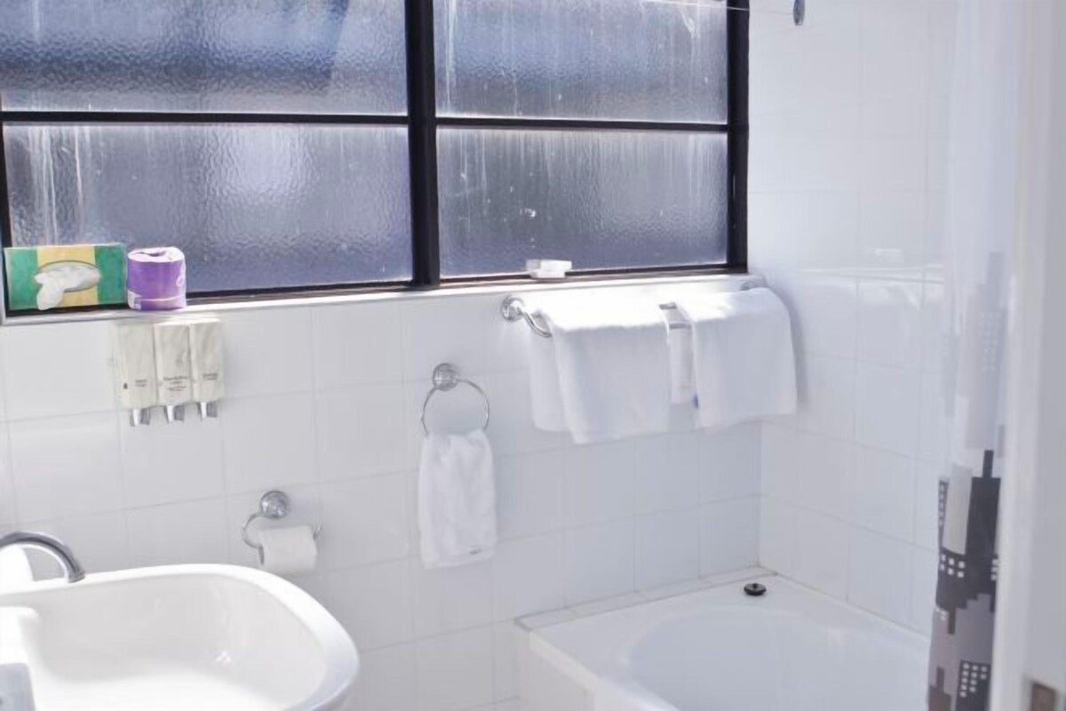 A bathroom with a bathtub, a sink, and a window with frosted glass panes.