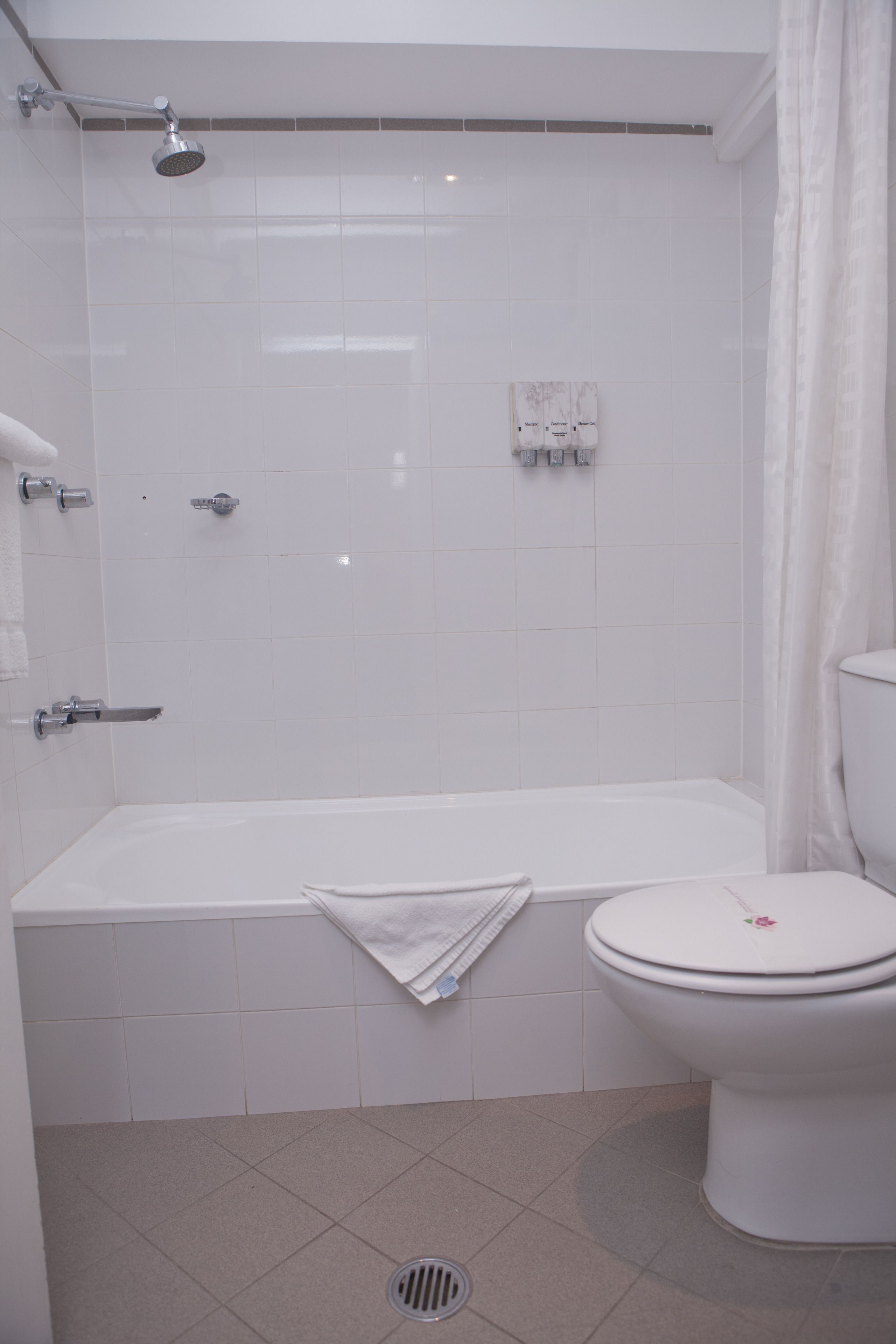 Ein Badezimmer mit Badewanne, Toilette, Duschkopf und Handtuchhalter.