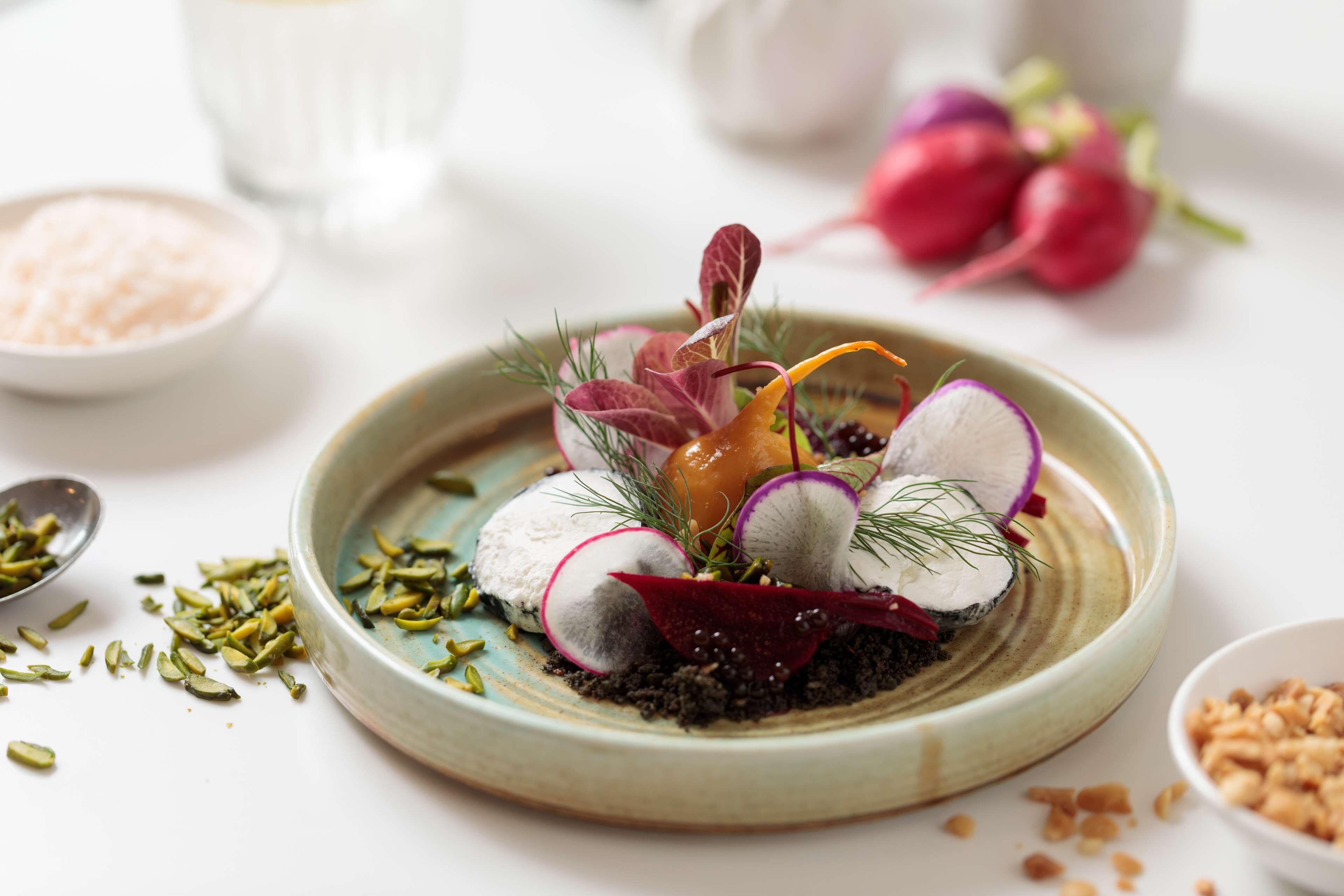 A plate of food with various garnishes and a small bowl of salt.