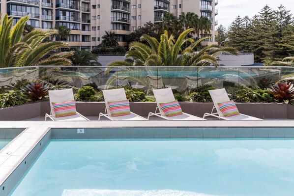 Relax by the pool surrounded by lush greenery and palm trees.
