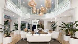 Eine geräumige Lobby mit einer zentralen Sitzecke, Glasgeländern und Topfpflanzen.