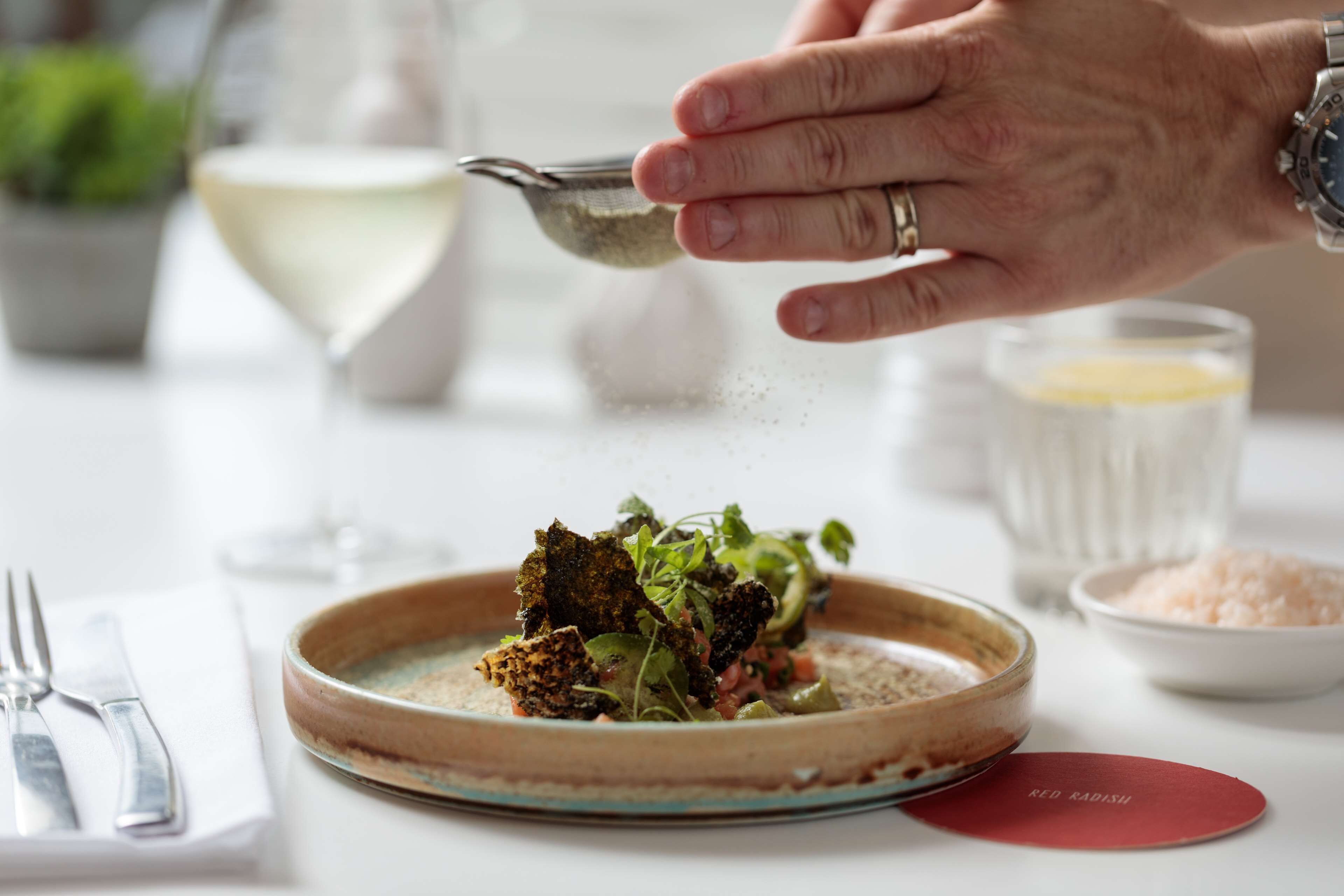 A person seasoning a dish with salt.