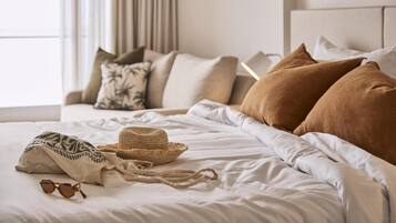 Una cama bien tendida con un sombrero de paja, gafas de sol y un tejido estampado.