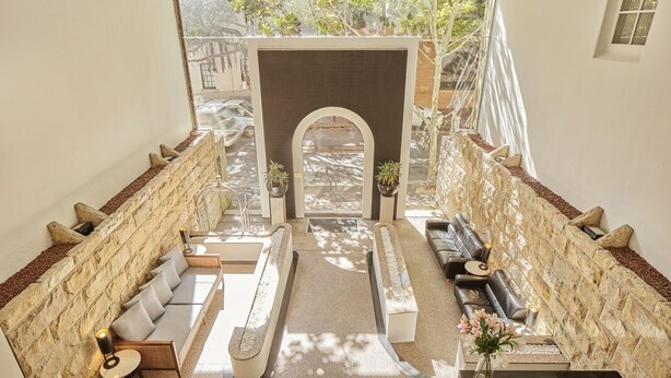 A modern interior with a central seating area, stone walls, and a view through a glass door. - Rendezvous Hotel Sydney The Rocks (The Rocks)