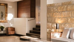 A spacious lobby with a stone wall, a staircase, a sofa, and a mirror. - Rendezvous Hotel Sydney The Rocks (The Rocks)