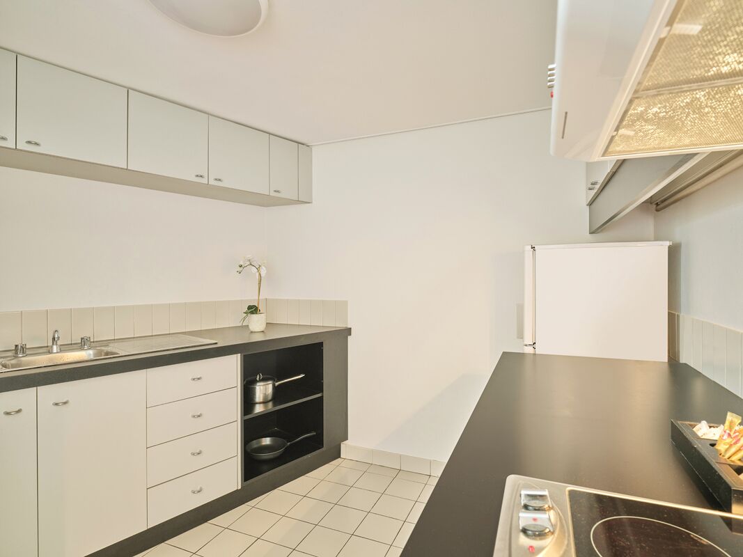 A modern kitchen with white cabinets, a black countertop, and a built-in oven.