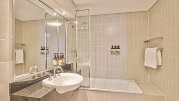 Ein modernes Badezimmer mit einer gläsernen Duschkabine, einem Waschbecken mit Marmorplatte und einer Badewanne.
