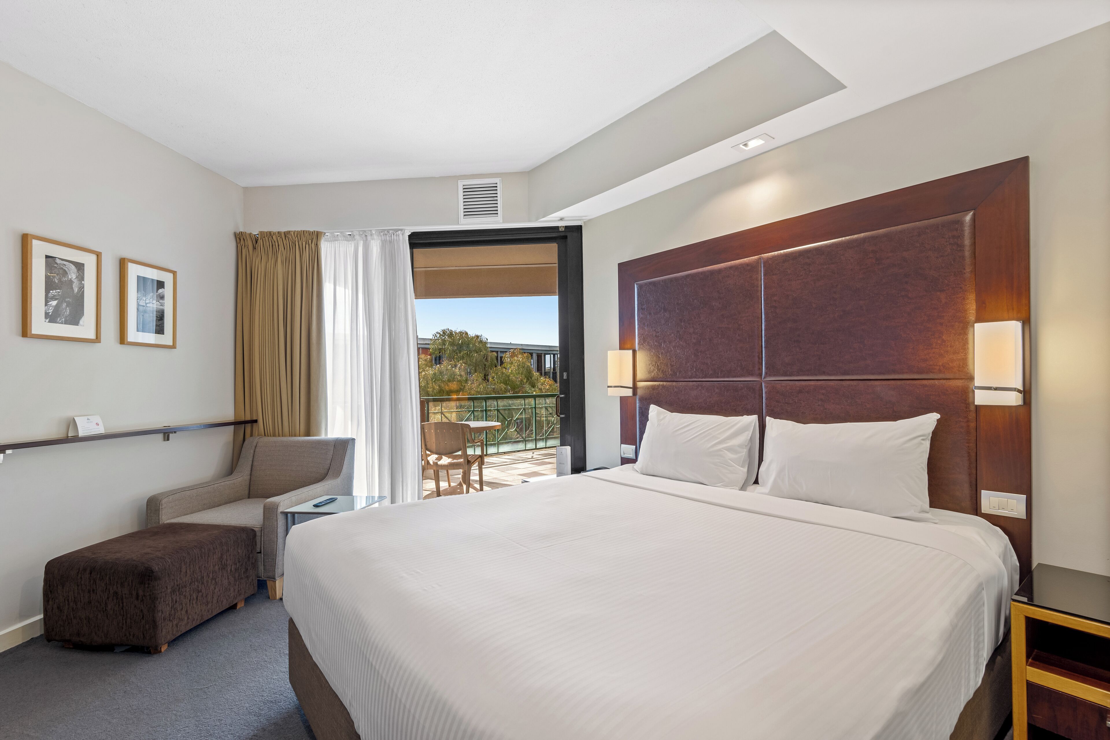 Una habitación de hotel con una cama grande, un escritorio, una silla y un balcón con vistas.