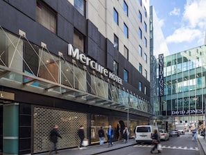 Un moderno edificio de hotel con un letrero destacado del Hotel Mercure y de la tienda David Jones.