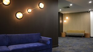 Un moderno vestíbulo de hotel con un sofá azul, un banco de madera e iluminación empotrada.