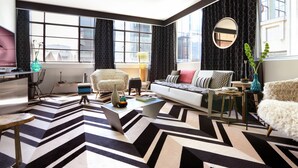 A modern living room with a large window, a sofa, a coffee table, and a chair. - Adelphi Hotel (Melbourne)