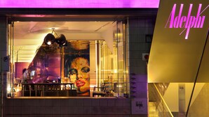 A modern hotel interior with a large glass window, a reception desk, and a neon sign. - Adelphi Hotel (Melbourne)