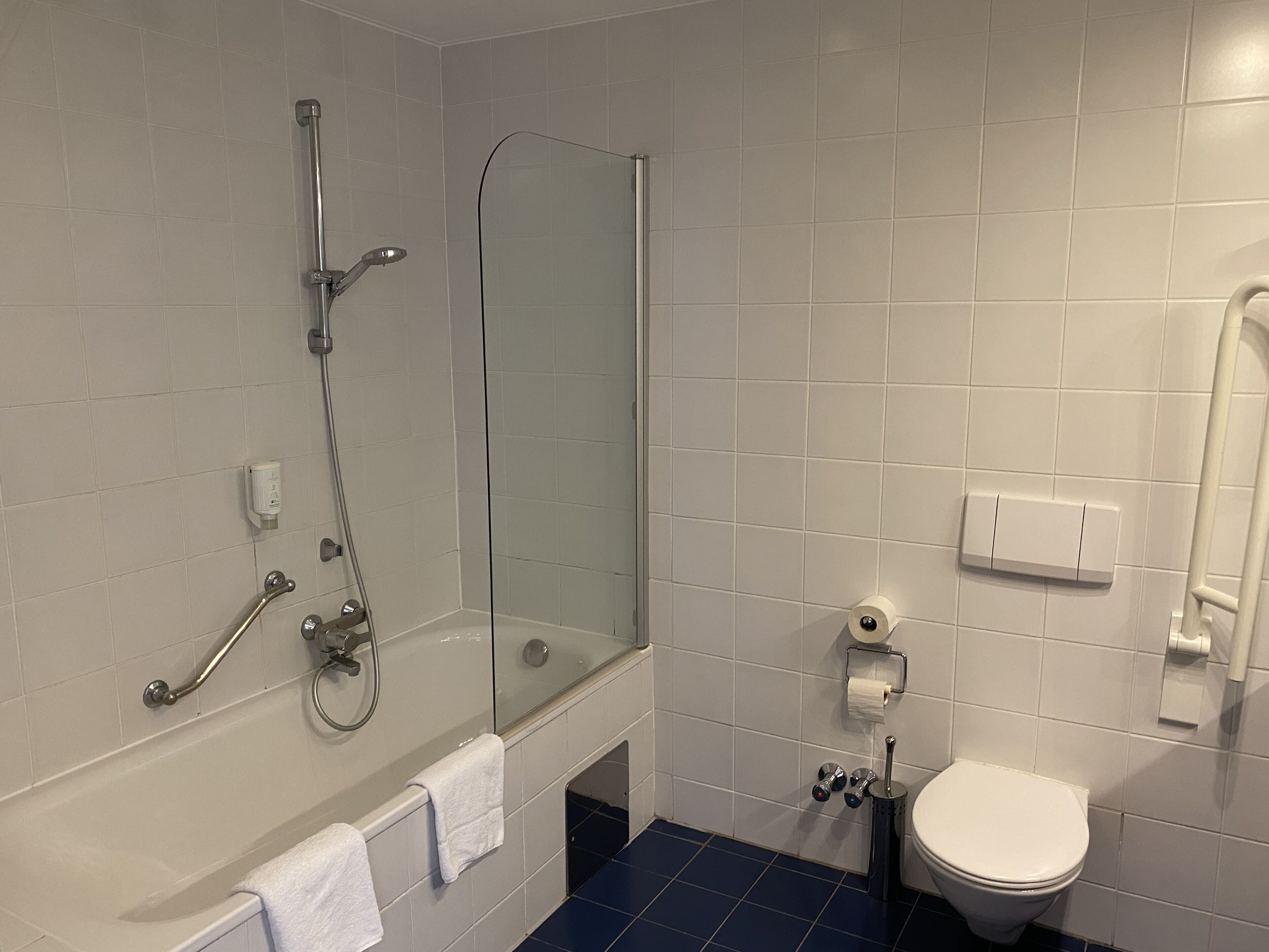 Ein Badezimmer mit Badewanne, einer Duschkabine, Toilette und einem Handtrockner.