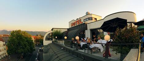 A hotel with outdoor seating and a view of the surrounding area.