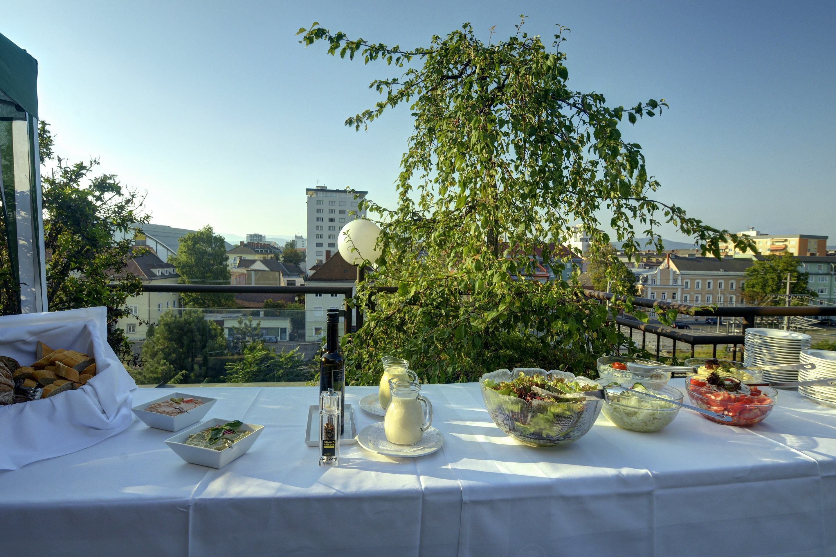 Una mesa dispuesta con diversos platos y bebidas en un balcón con vista a la ciudad.