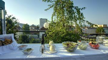 Una mesa dispuesta con diversos platos y bebidas en un balcón con vista a la ciudad.