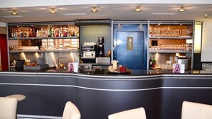 A bar area with a counter, bar stools, and shelves stocked with bottles and glasses. - Skycity Hotel Atrigon (Klagenfurt am Woerthersee)