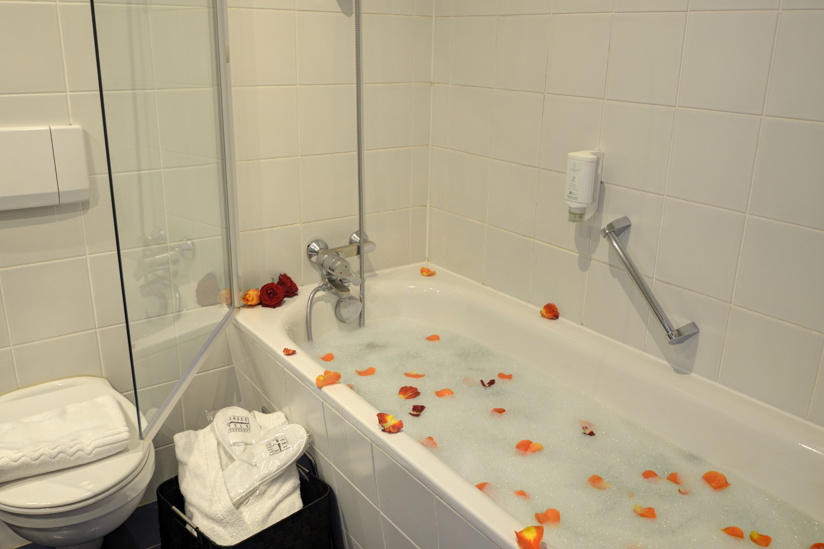 A bathroom with a bathtub, toilet, and glass shower enclosure.