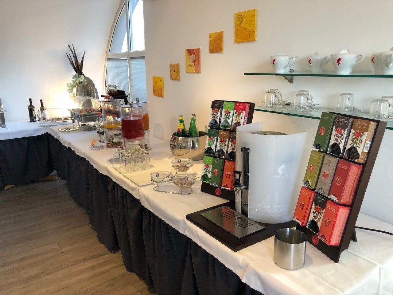 A well-organized buffet table with various food items, a coffee station, and a selection of tea boxes.