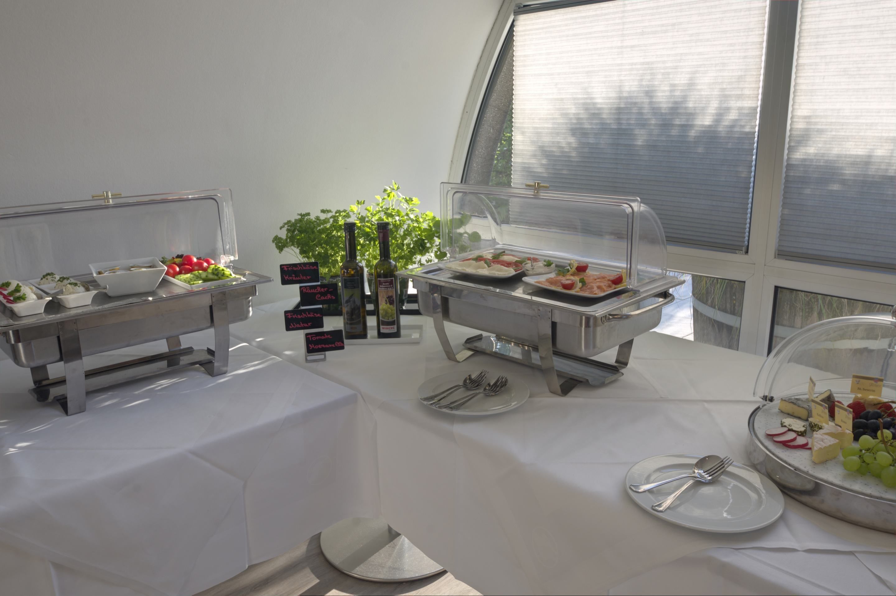 A buffet setup with various food items and condiments, arranged on a table with a clear glass cover.