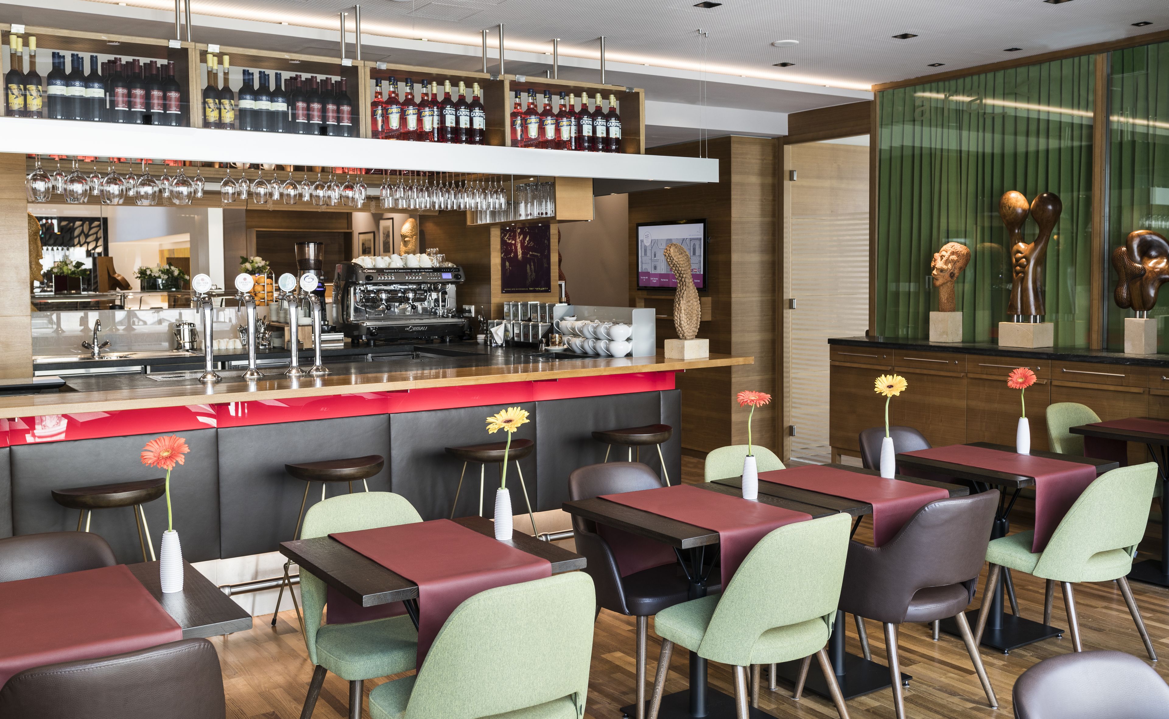A modern bar area with a variety of liquor bottles, a coffee machine, and bar stools.