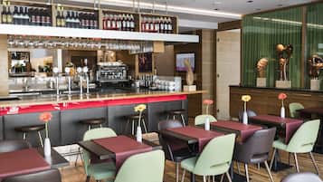 A modern bar area with a variety of liquor bottles, a coffee machine, and bar stools.