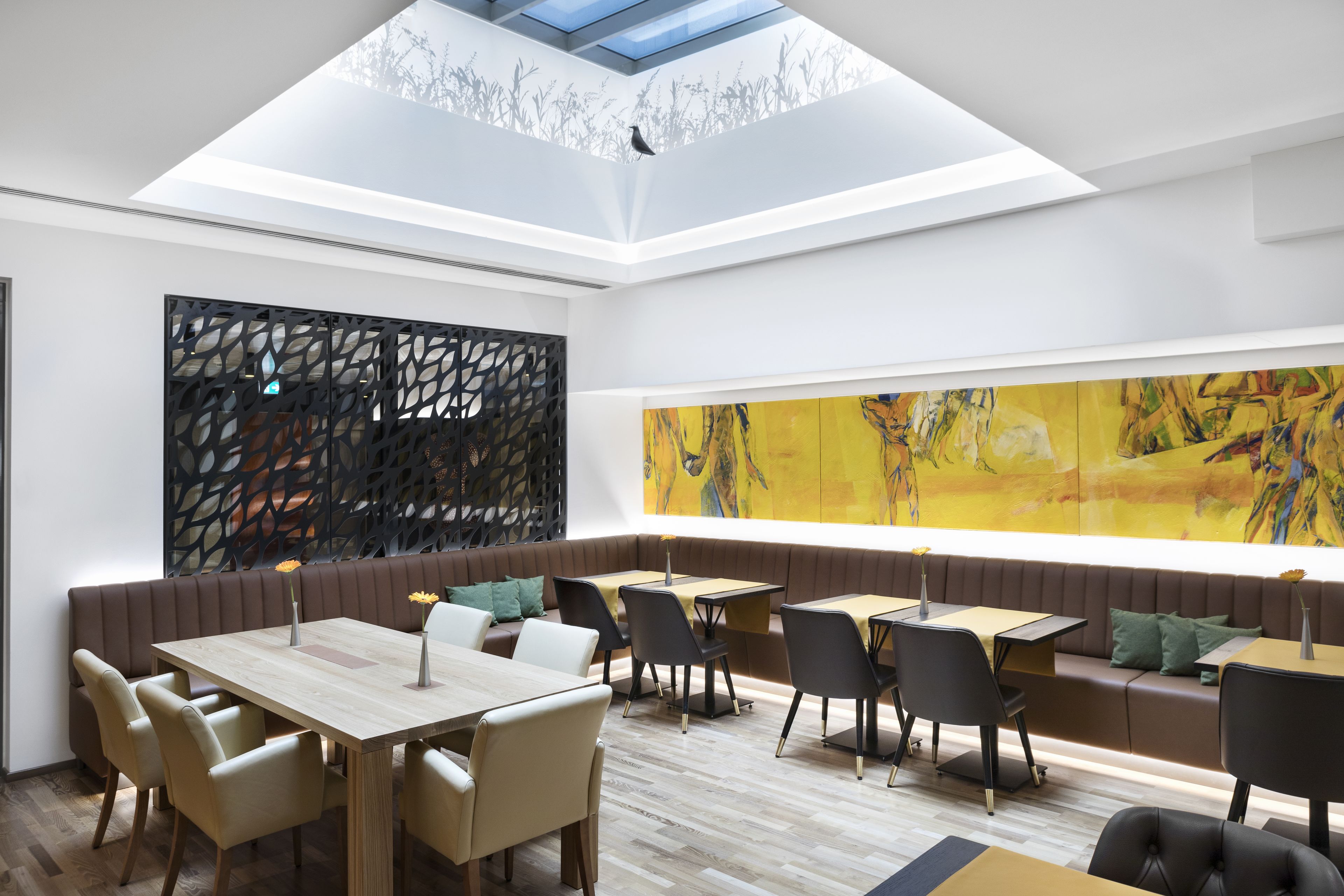 Un restaurante moderno con techos altos, tragaluces y un cuadro abstracto de grandes dimensiones.