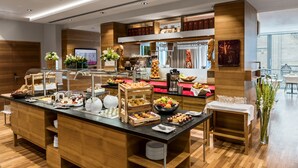 A buffet setup with various food items, a coffee station, and a seating area with a view. - Boutique Hotel Am Stephansplatz (Vienna)